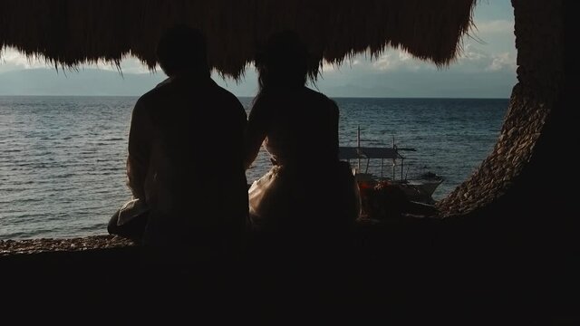 backshot silhouette of two lovers looking out at sea ocean