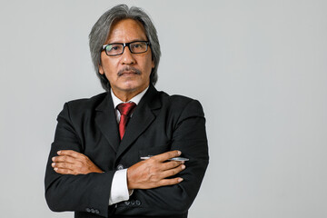 Senior staff with white hair wearing mustache glasses Standing with fierce expression in a black suit a red tie holds the pen at the right hand. On white backdrop