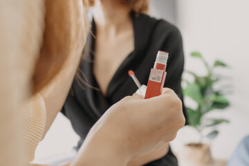 Asian makeup artist is applying lipstick to the clients.