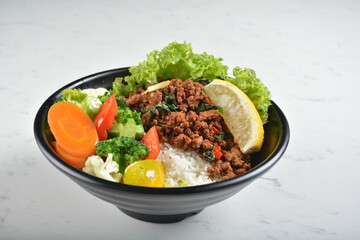 asian spicy thai basil minced pork rice bowl with fried vegetable salad in black bowl in white marble healthy poke bowl menu