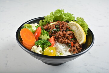 asian spicy thai basil minced pork rice bowl with fried vegetable salad in black bowl in white marble healthy poke bowl menu
