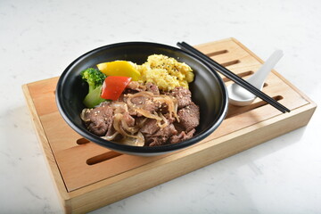 stir fried bbq bulgogi beef rice bowl with scrambled eggs and fried vegetable salad in black bowl...