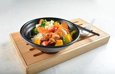 hawaiian sweet & sour grilled chicken pineapple rice bowl with fried vegetable salad in black bowl in white marble healthy poke bowl menu