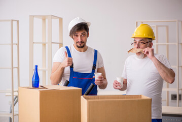 Two male professional movers drinking alcohol during break