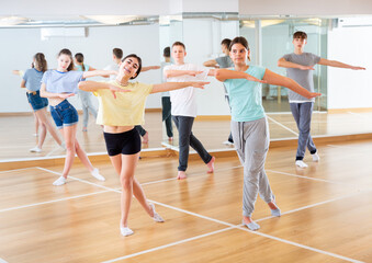 Fototapeta na wymiar Diligent friendly smiling teenagers learn dance movements in dance class