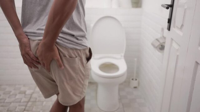 male with stomach ache having a diarrhea standing in toilet and hands hold his butt painfully.
