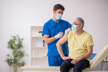 Fototapeta premium Old male patient visting young male doctor in vaccination concep