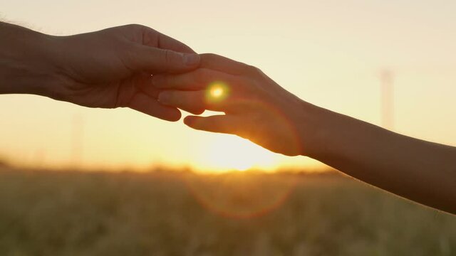 Silhouette people helping of two hands reaching out each other at sunset