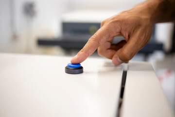 Close up view of worker's hand pressing button on industrial machine.