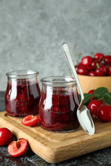 Cherry jam and ingredients on black smokey table