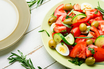 Salad with vegetables, olives, eggs and rosemary