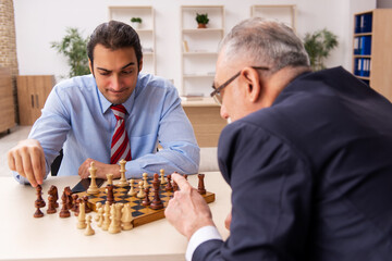 Two businessmen playing chess in the office