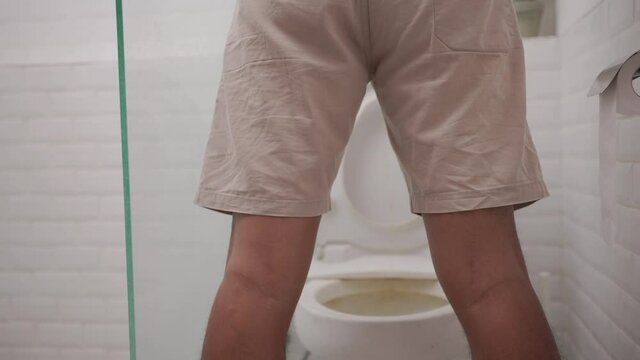 a man peeing standing up in the restroom shoot from behind