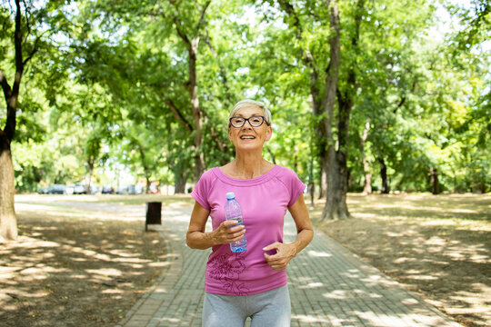 Smiling senior caucasian woman jogging in the park. - Powered by Adobe