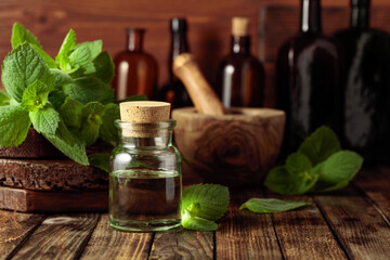Fresh spearmint leaves and a small bottle with essential mint oil.