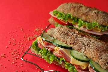 Baking rack with ciabatta sandwiches on red background