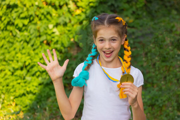 cheerful cute girl rejoices in victory and holds a medal for first place in her hands