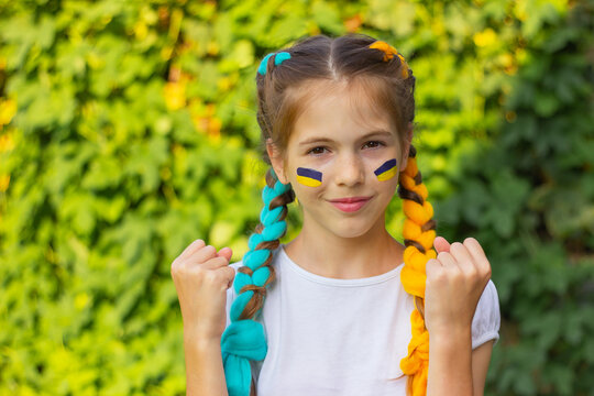 joyful Ukrainian girl with blue and yellow flags painted on her cheeks. the concept of patriotism, flag day and independence day of Ukraine. sports and fan support.