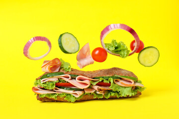 Ciabatta sandwich and ingredients on yellow background