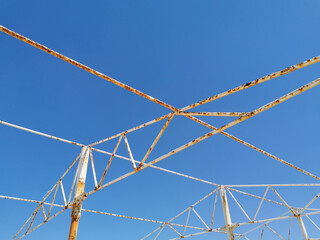 an angular drawing of a structure made of old rusty peeling white pipes and beams against the...