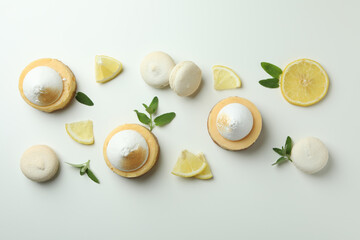 Lemon cupcakes, macaroons and ingredients on white background