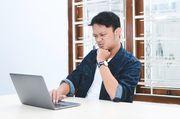 Fototapeta premium Young Asian man angry and mad what he see in the laptop when work