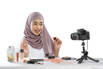 Beauty blogger in hijab recording video for her blog against beige background