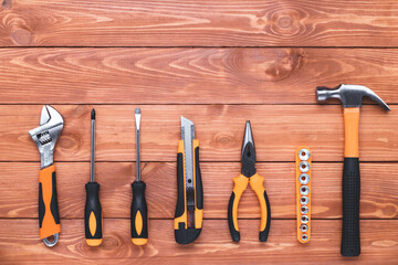 Set of construction tools on a brown wood background. Hammer, wrench, pliers and screwdriver. Frame border, postcard for the holiday Labor Day. Equipment, workplace. Flat design, copy space.