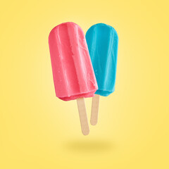 Red and blue ice creams flying on yellow background with copy space. Summer background
