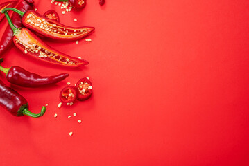 Fresh red chilli peppers  and peppers slices isolated on red background. Top view.