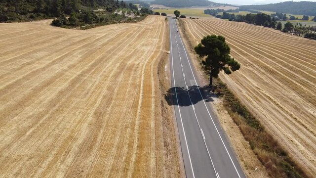 Tomas Aereas y Cenitales de carretera desierta ente campo de trigo cosechado, con pas de motos y ciclistas