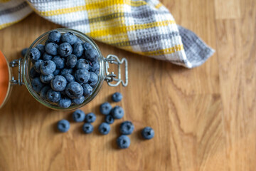 Glass jar  with blueberries on the wooden background, top view