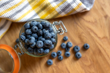 Glass jar  with blueberries on the wooden background, top view