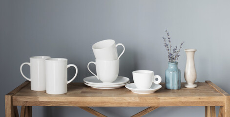 white cups and vases on wooden shelf on gray background
