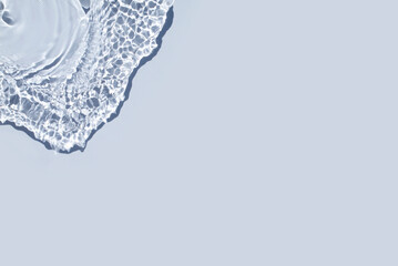 Rippled water light blue backdrop. Background with sun reflection for cosmetic concept. Transparent blue trendy banner with place for text. Micellar water or toner texture