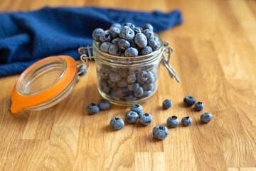 Blueberries in glass jar on a wooden background