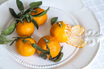 new Year's tangerines with leaves on a white plate