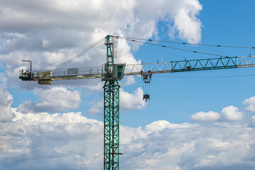 Green construction crane on a sky background
