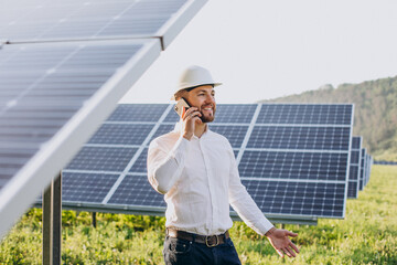 Young architect standing by solar panels talking on the phone © Petro