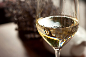 Glass of white wine close up. Alcoholic drink on a wooden table on a background of the city. Transparent wine on the summer terrace of the restaurant.