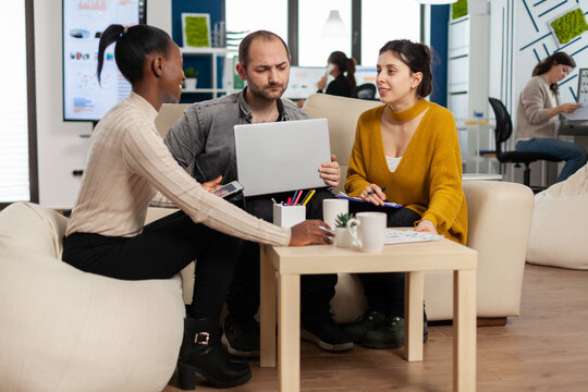 Group of diverse startup company colleague entrepreneur sitting on couch in professional workplace, brifing and sharing ideeas over financial strategy management. Employees working together at office.