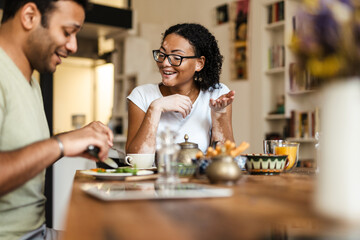 Middle eastern man and woman smiling while having breakfast at home