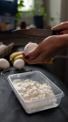 female hand breaks egg in pot