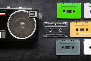 Top view half retro radio and colorful cassette tape on black floor with copy space