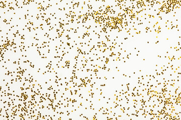 Festive or glamorous background. Gold sparkles scattered on a white background.