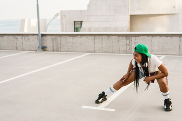 Obraz premium Black young woman with headphones dancing on parking