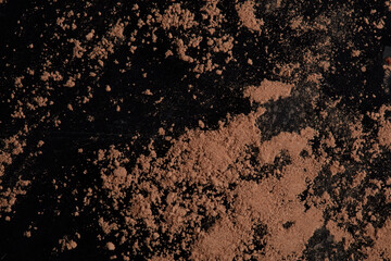 Brown cocoa powder scattered on a black background.