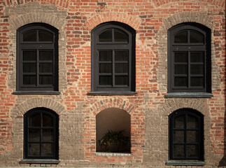 Brick wall of an old building with arched windows.
