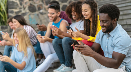Young multiracial group of friends using mobile smartphone sitting on stairs - Youth millennial lifestyle concept