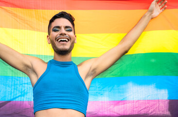 Happy homosexual man celebrating gay pride holding rainbow flag symbol of LGBTQ community
